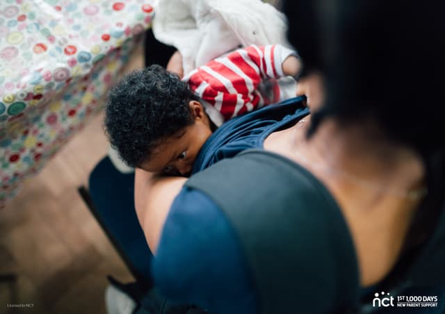 Image shows a person breastfeeding an infant